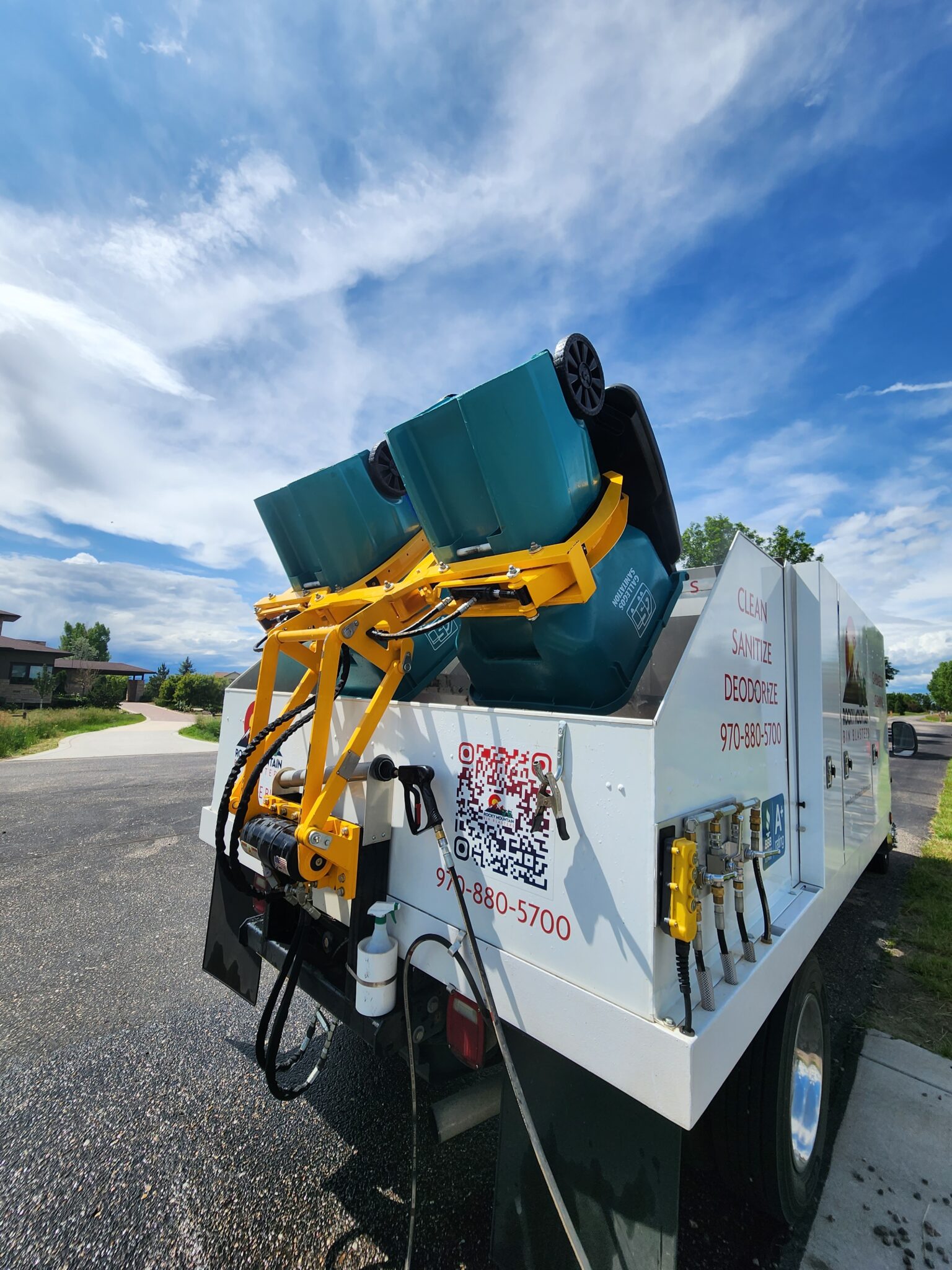RMBB truck lifting green bins with its cleaning arms